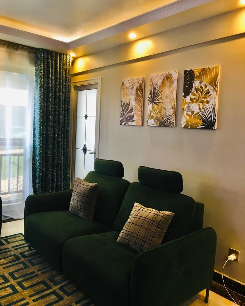 A row of framed prints above a green sofa